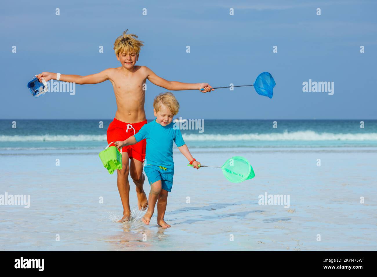 Kids Walk On A Beach Hold Buckets And Hoop Net Catching Crabs Stock